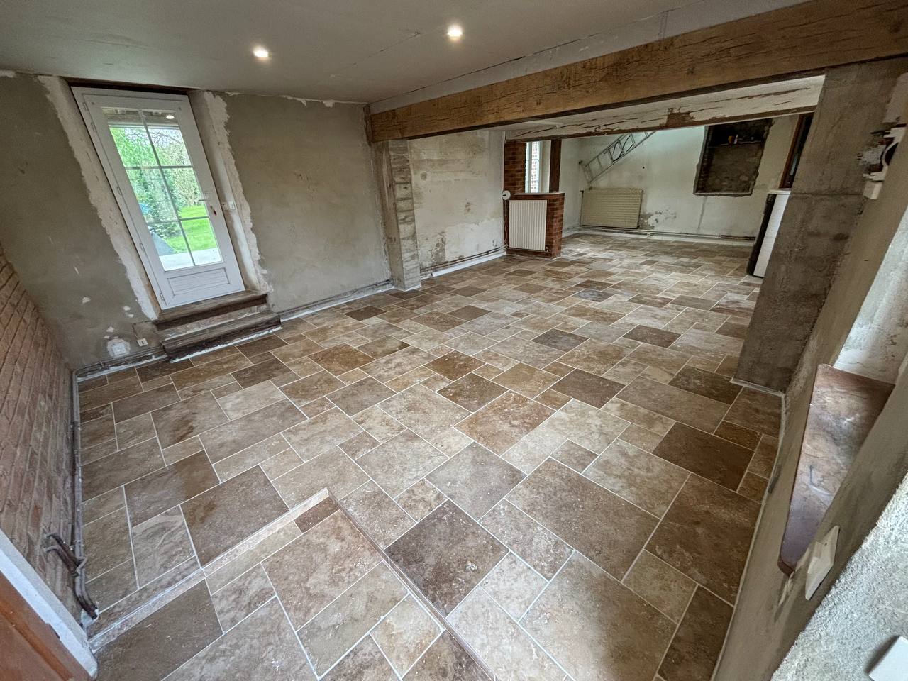 Pièce rénovée avec carrelage posé et murs repris