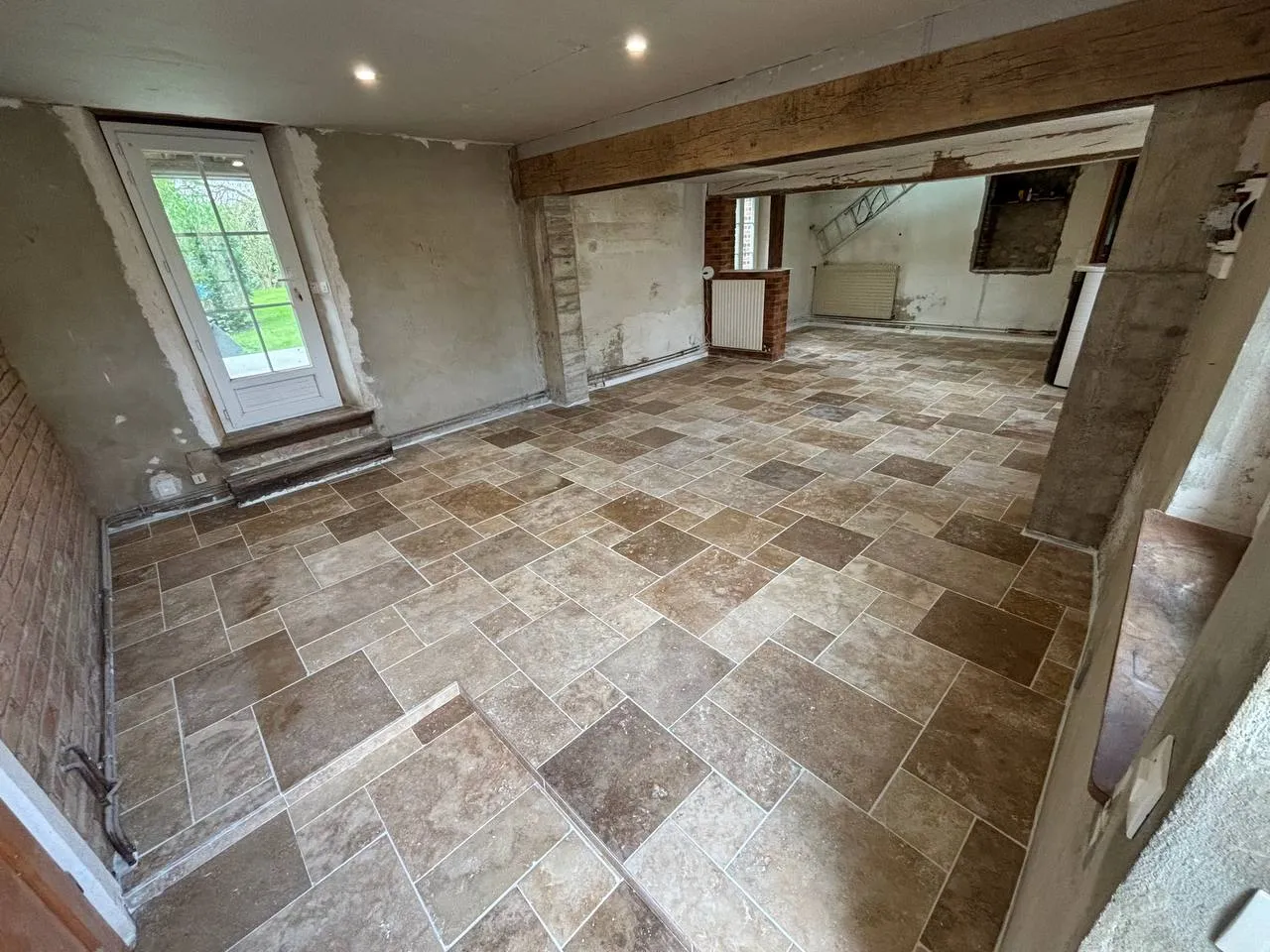 Pièce rénovée avec carrelage posé et murs repris